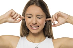 Young annoyed woman sticking fingers in ears