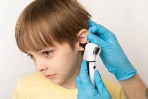 Pediatrician examines childs ears with an othscope in clinic