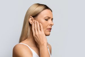 Tinnitus. profile of sick female middle aged blonde woman having strong ear pain
